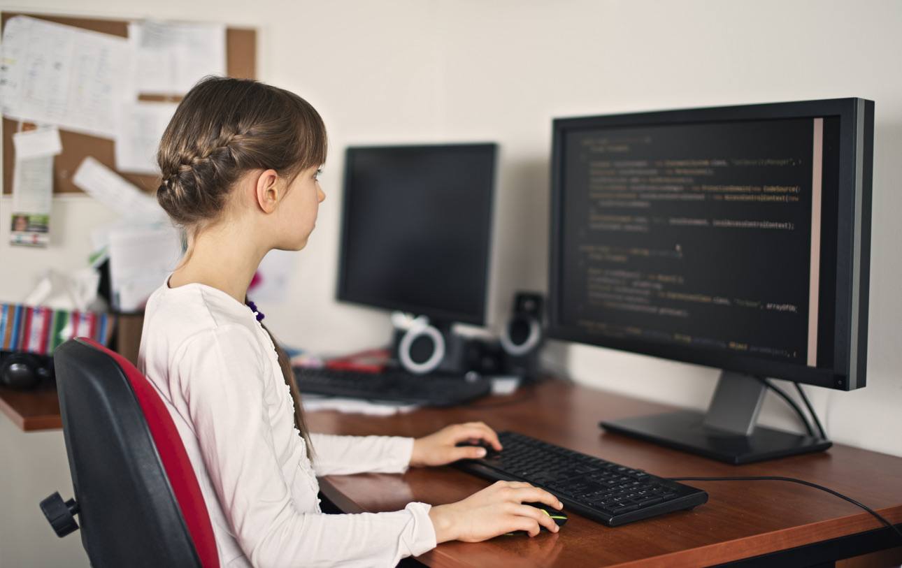 Smiling girl sitting at a laptop and coding