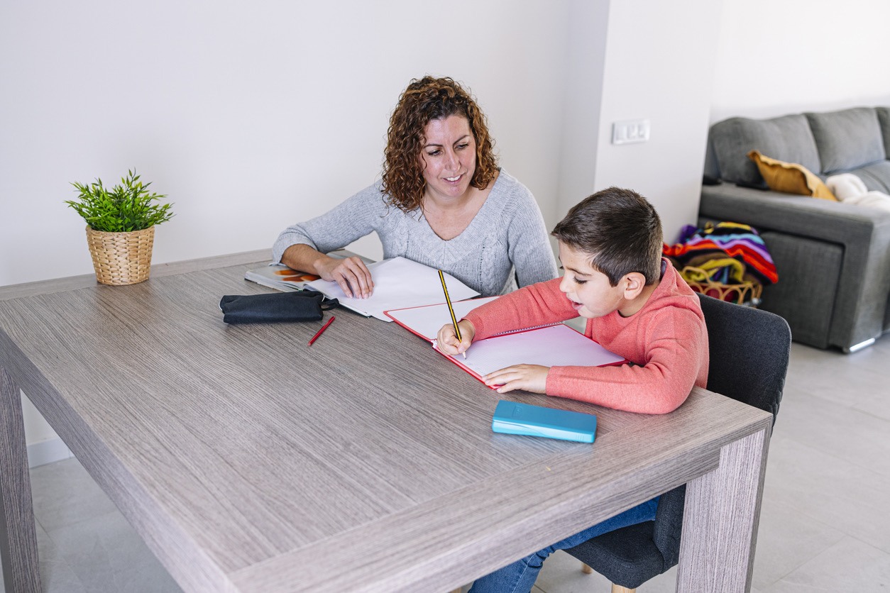 Mother overseeing her son's homework at a modern home desk.