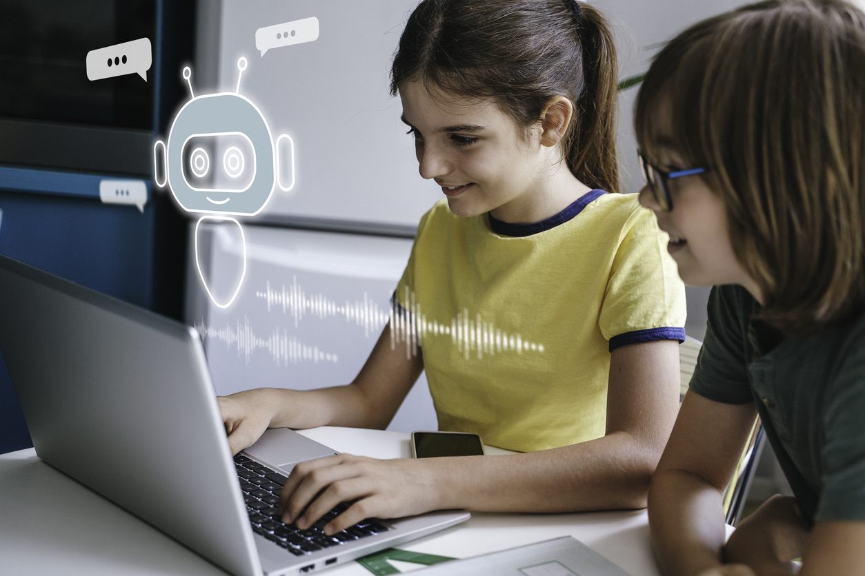 Two children interacting with a laptop displaying a chatbot interface