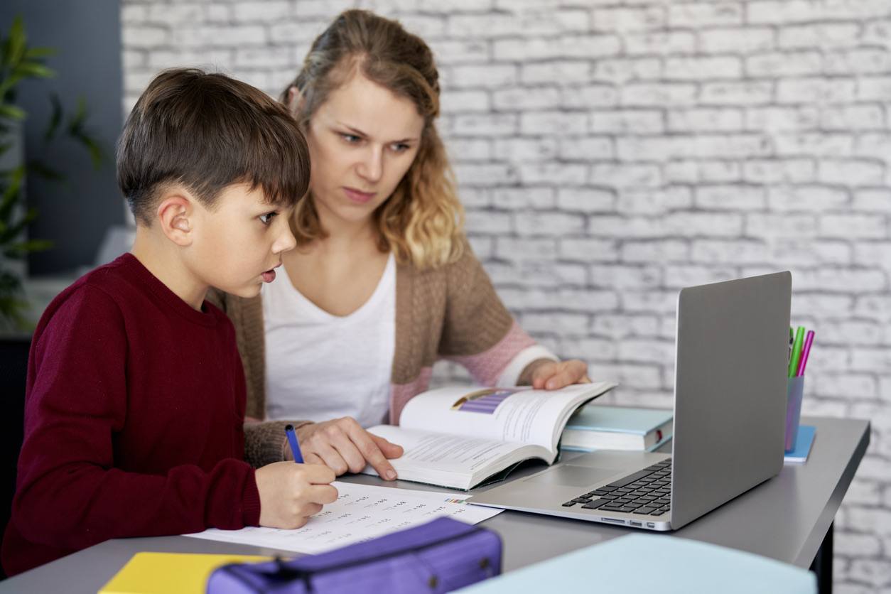 Mother and son working on educational activities together on a laptop.