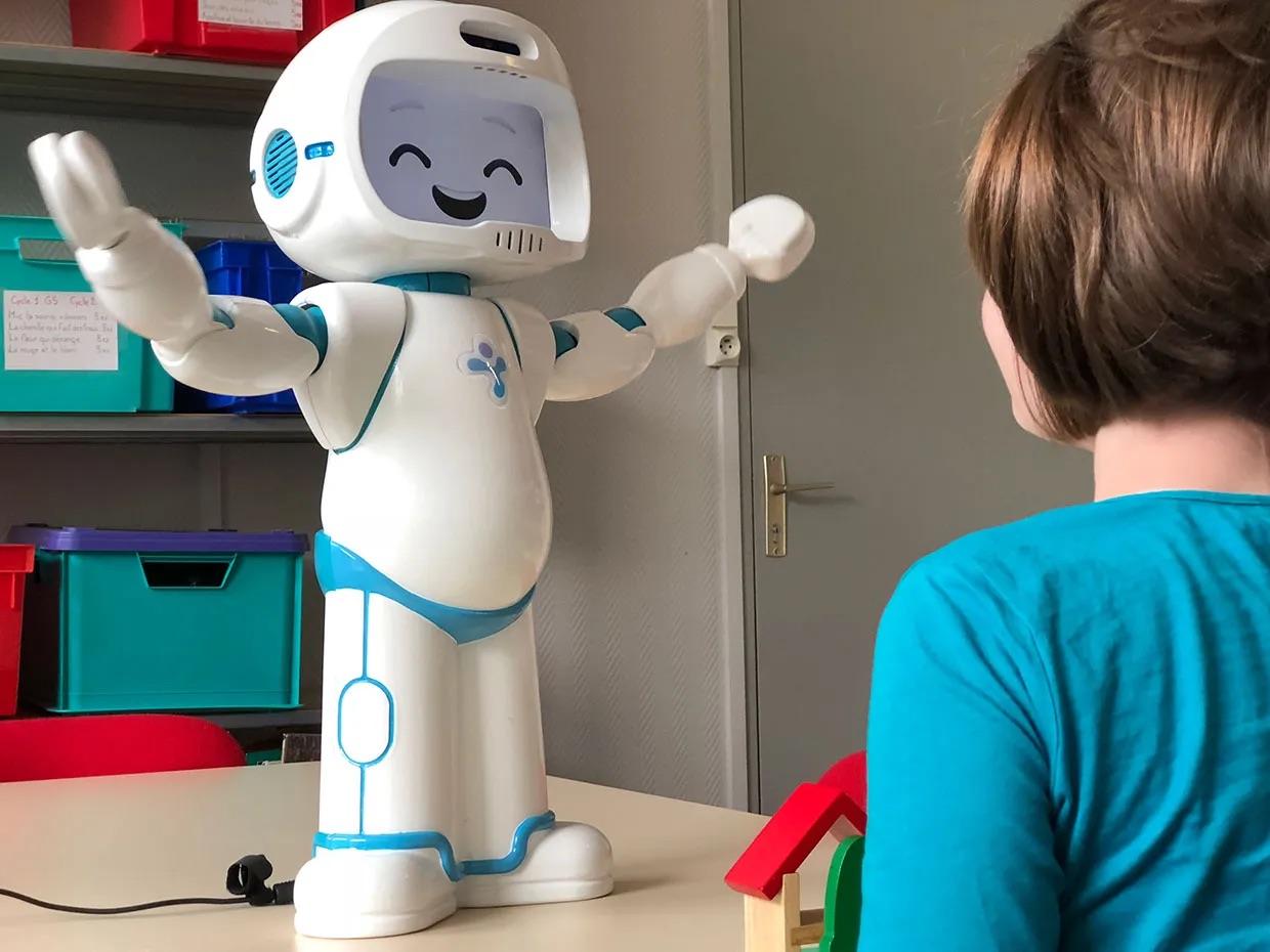 Child interacting with a humanoid robot in a classroom setting.