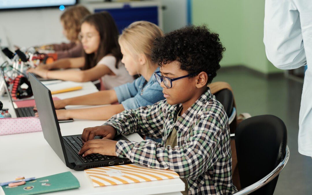 Group of elementary students coding on laptops in a classroom