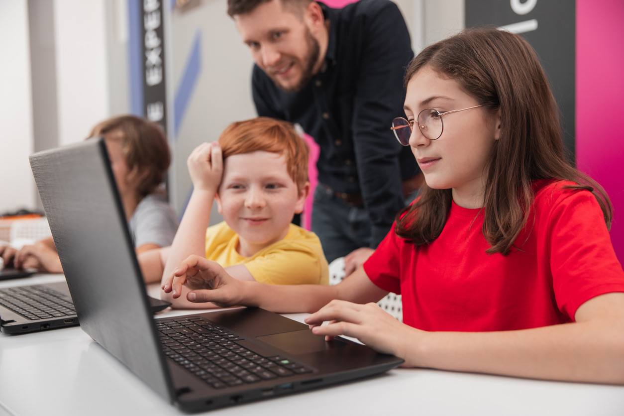 Children learning coding with teacher supervision