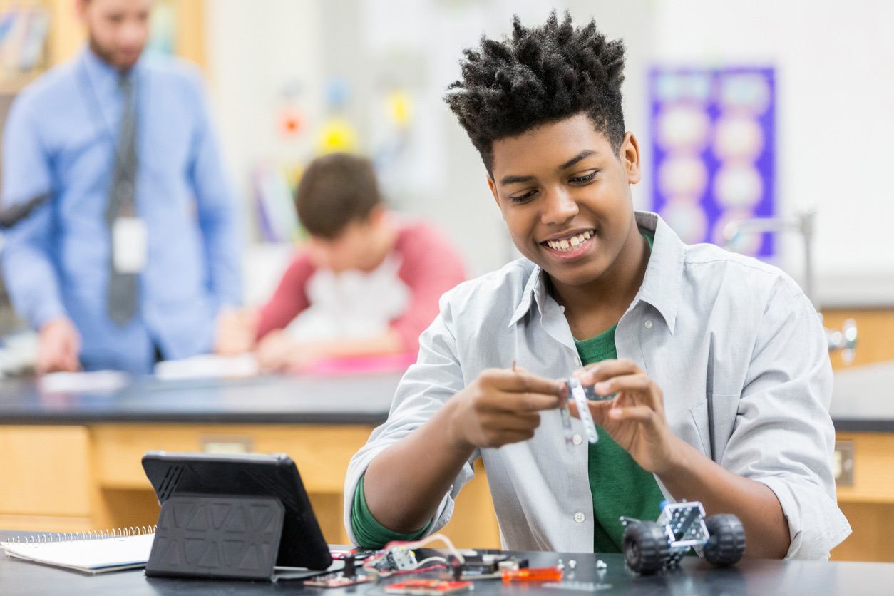 Teenager building robot in classroom to learn AI and coding